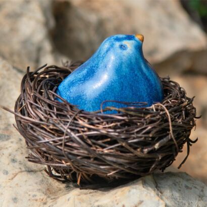 Glazed blue stoneware bird in a natural fiber nest